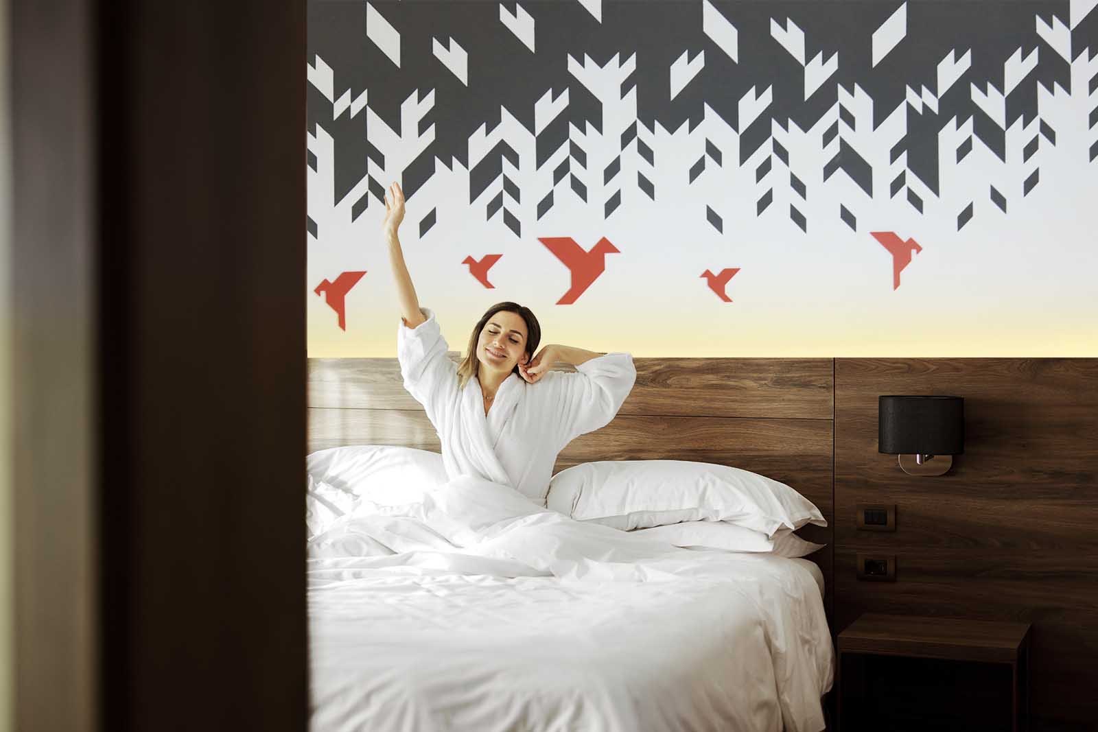 Happy woman in white nightwear sitting in bed awakened from enough and healthy sleep feels good, stretching her arms muscles after sleep and long immobility wakes up start new day with smile